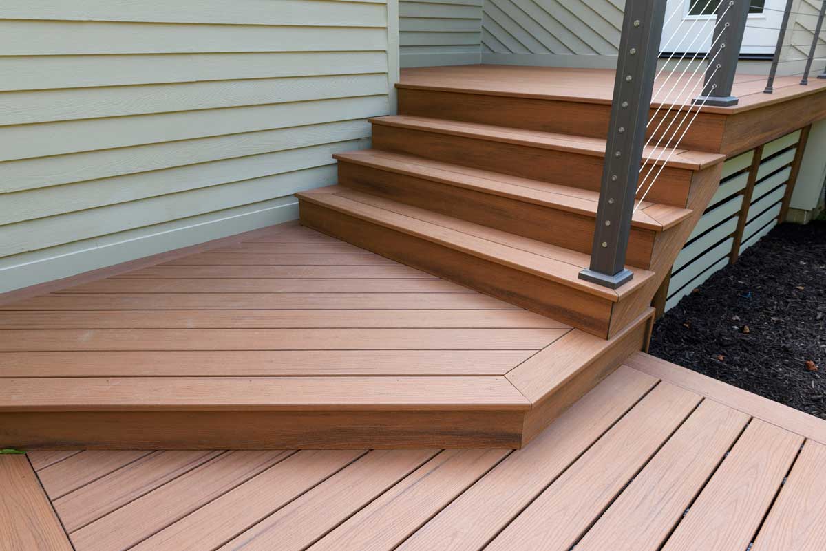 A composite deck with a small stair made of a glossy orange-brown wood