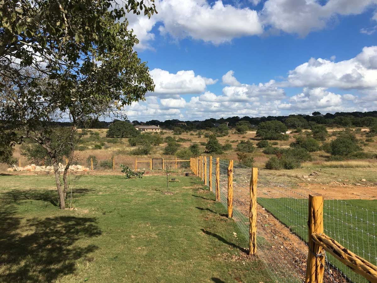 A wood and wire fence around the yard of a ranch