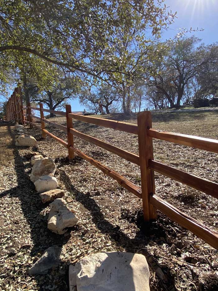 A split-rail fence going up a hillside covered in trees