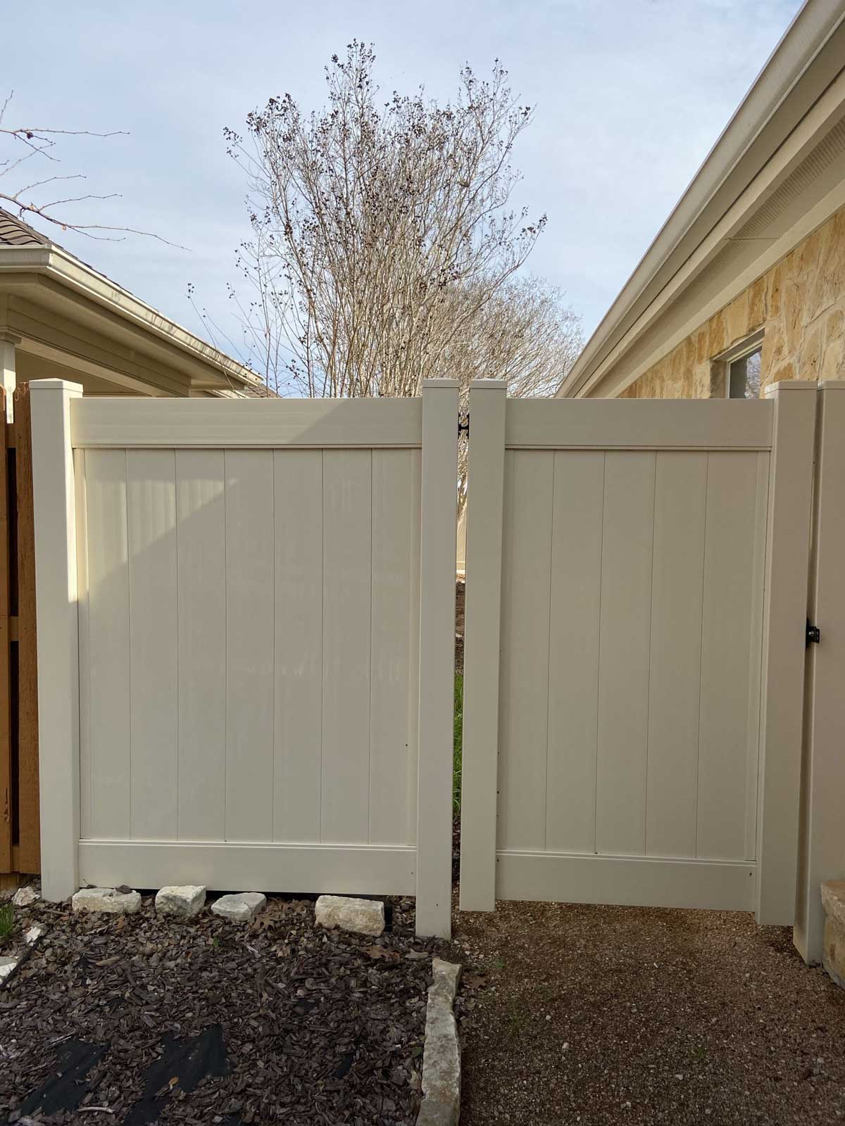 A white vinyl gate in a side-yard